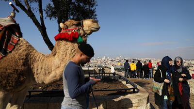A man stands next to a camel as tourists visit an observation point on Mount of Olives overlooking Jerusalem's Old City. Ammar Awad / Reuters