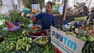 A vendor weighs vegetable next to an advertisement of Paytm - the digital payments firm is among Indian companies that received foreign investment. Reuters
