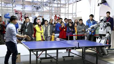People look on as a robot plays table tennis with a man during an demonstration at the World Robot Conference. Reuters