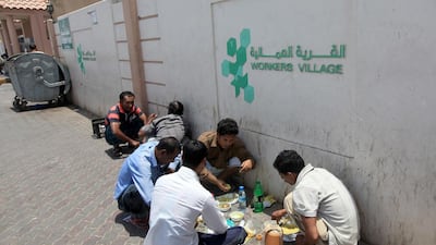 Labourers sit outside their labour camp under the blistering sun as they say there are not allowed to carry food into their accommodation at the Workers Village in Mussaffah, Abu Dhabi. Ravindranath K / The National