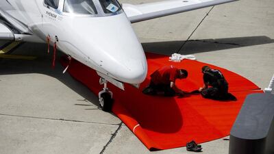 Worker install red carpet next to an Embraer executive jet at the static display at EBACE. Fabrice Coffrini / AFP