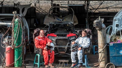 Jacques Barron, left, and his son and co-driver Lucas Barron, 25, pose at a mechanics workshop in Lima ahead of the 2019 Dakar Rally. AFP