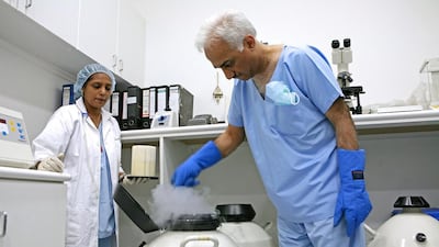 Dr Pankaj Shrivastav, right, and Farhat Unnisa at the Conceive Fertility Center in Sharjah with a cannister containing frozen embryos. Randi Sokoloff / The National