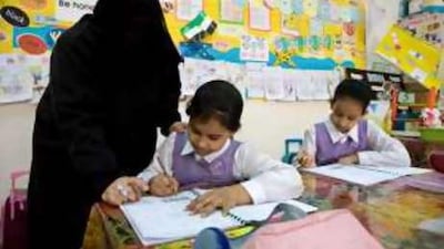 Third grade pupils work on assignments with assistance from their teacher at Khadeeja Al Kubrah Primary School.