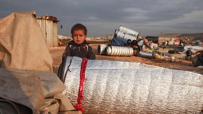 A child stands behind rolled-up thermal insulation foil out in the open at a camp for displaced Syrians east of Sarmada in the north of the northwestern Idlib province as people prepare to flee the camp. AFP