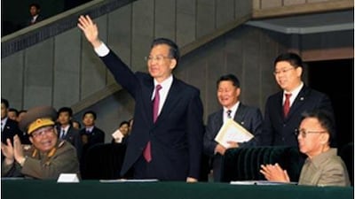 This picture released from North Korea's official Korean Central News Agency shows the Chinese prime minister Wen Jiabao (centre) waving as he watches a game with the North Korean leader Kim Jong Il (right) at May Day Stadium in Pyongyang on October 5, 2009.