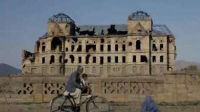 An Afghan woman begs for alms in front of the ruins of the Darul Aman palace in Afghanistan.