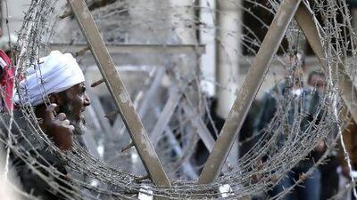 An opponent of president Mohammed Morsi, left, argues with Morsi supporters as the Egyptian Army deploys near the presidential palace.