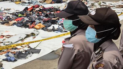 Indonesian police officers guard wreckage.