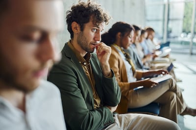 Candidate waits nervously for a job interview with others. Getty Images