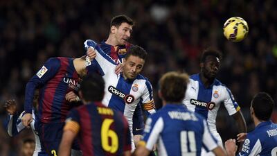 Lionel Messi, top, of Barcelona heads the ball over Espanyol's Sergio Garcia during their La Liga match on Sunday night. Lluis Gene / AFP