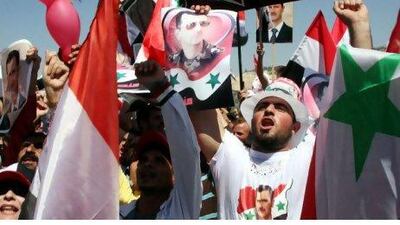 Pro-governement demonstrators hold posters of President Bashar Al Assad and wave the Syrian flag during a rally held in Damascus yesterday. Youssef Badawi / EPA