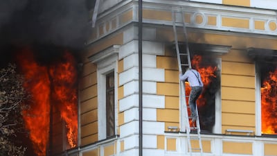 A man descends a ladder to escape a fire at the National Academy of Sciences building in Kyiv, Ukraine. AFP