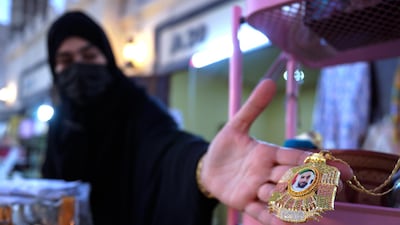 Mariam Al Shehi displays a Sheikh Zayed medallion for sale at her stall at the Sheikh Zayed Heritage Festival.