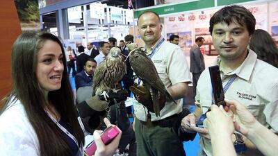 Visitors pose with falcons at the Slovakia stand during the Arabian Travel Market in Dubai. Satish Kumar / The National