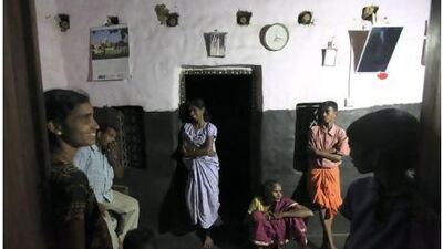 Pushpa Gowda, centre, and her mother, Boommi Gowda, seated, shares a light moment with her family and neighbours the evening after they installed solar light in her house in Nada, on the outskirts of Mangalore. Rafiq Maqbool / AP Photo