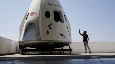 An attendee takes pictures of a mock up of the Crew Dragon spacecraft. Bloomberg