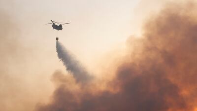 A chinook helicopter makes a water drop as a wildfire continues to rage in Varympompi, north of Athens.