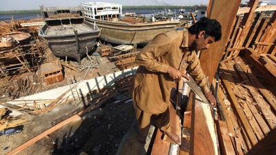 A carpenter cuts out a wood panel while working on a boat in Karachi's Fish Harbour. Akhtar Soomro / Reuters