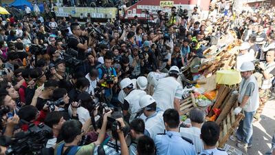Workers, in white, remove barricades in a blocked section of Argyle Street in Mong Kok. Hong Kong bailiffs have been enforcing a court order against a protest camp and have successfully torn down barricades at an intersection in Mong Kok. Jerome Favre / EPA