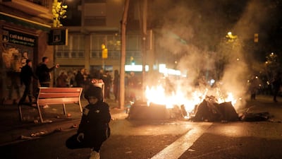 A boy poses in front of fires burning at the Catalan pro-independence protest. AP