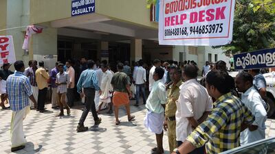 Indian bystanders and relatives gather near a banner announcing a help desk for the queries of relatives of injured or deceased victims of the Puttingal Devi Temple fire trajedy in front of the casualty ward at Kollam District Hospital in Kollam. Manjunath Kiran / AFP