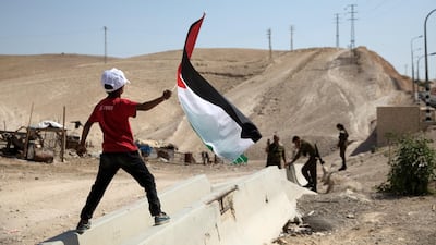 A Bedouin boy waves a Palestinian flag in front of Israeli soldiers at Khan Al-Ahmar. Reuters