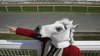 A Japanese fan with a horse mask points the direction of the track as he and another Japanese fan with a mask. Kamran Jebreili/ AP Photo