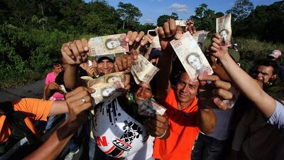 Venezuelans hold up 100-bolivar notes during a protest in San Cristobal in Venezuela’s Tachira state on December 16, 2016. George Castellanos / AFP