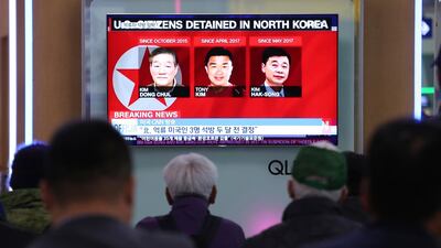 People watch a TV news report screen showing portraits of three Americans, Kim Dong Chul, left, Tony Kim and Kim Hak Song, right, detained in the North Korea, at the Seoul Railway Station in Seoul. Ahn Young-joon / AP