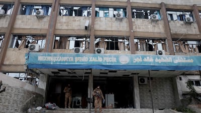 An armed Syrian security officer stands outside the Khaled Fajr Hospital in the Al Sheikh Maqsoud neighbourhood. It had been attacked by machine guns and drones. AFP