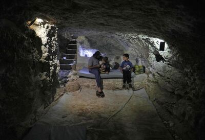 Syrian Hadheefa Al Shahadh, 27, sits with his children in a cave that he dug inside his house to shelter him and his family against raids in rebel-held Idlib. Omar Haj Kadour / AFP