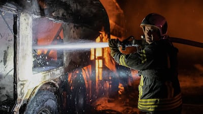 A firefighter tries to put out fire caused by fragments of a Russian rocket after it was shot down by air defense system during the night Russian rocket attack in Kyiv, Ukraine. AP