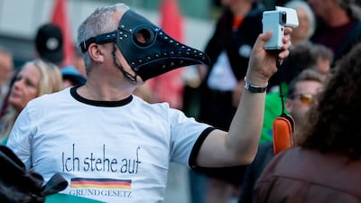 A man with a beak mask holds a camera at a rally against coronavirus measures on Thursday, August 27, 2020. The rally was a prelude to a demonstration expected on Saturday. Police in Berlin have requested thousands of reinforcements from other parts of Germany to cope with planned protests at the weekend by people opposed to coronavirus restrictions. dpa via AP