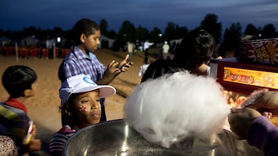 Children anxiously await their cotton candy on Family Day in the desert near Al Ain. Silvia Razgova / The National