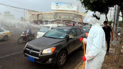 A Yemeni worker wearing a protective outfit sprays disinfectant on passing cars and motorcycles in the capital Sanaa, during the ongoing novel coronavirus pandemic crisis, on May 21, 2020. AFP