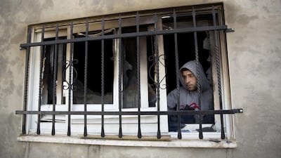 A Palestinian man looks out a window in a house that was torched in the Palestinian village of Duma near the West Bank city of Nablus, this month. Majdi Mohammed / AP Photo