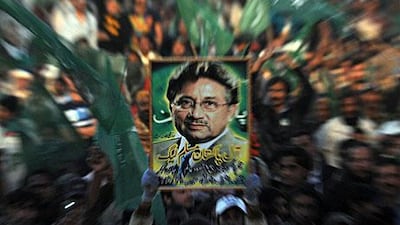 A supporter of the All Pakistan Muslim League, the party of the former Pakistan president, Pervez Musharraf, holds his portrait on Sunday during a public meeting in Karachi. Mr Musharraf has said he would return home by the end of this month after more than three years of self-exile.
