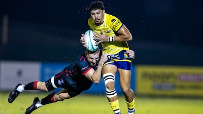 Aaron Dubois of Dubai Hurricanes is tackled by Michael Stubbs of Dubai Exiles.