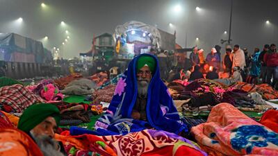 Farmers wrapped in blankets sit on a blocked highway as they continue to protest against the central government's recent agricultural reforms at the Delhi-Uttar Pradesh state border in Ghazipur. AFP