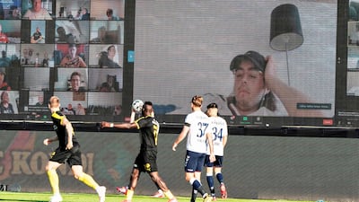 Players vie for the ball as fans and players are streamed live on to the screens on the sidelines during the 3F Super League football match between AGF and Randers FC at Ceres Park in Aarhus, Denmark. AFP