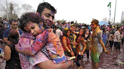 A father holds his tired daughter as a crowd of hundreds celebrates the Hindu festival of Holi during Rang de 2014 by rubbing chalk on themselves and others, dancing and splashing water at Wonderland Park. Jeff Topping / The National / March 14, 2014