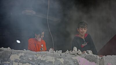 Syrian children watch the aftermath from their damaged balcony. AFP
