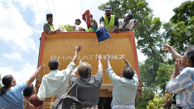 Residents collect food and water from a truck distributing relief to those stranded by floods in Pandanad, Kerala. AFP
