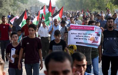Demonstrators march with placards in Beit Hanoun, northern Gaza Strip. Adel Hana / AP