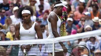 Venus Williams, right, wipes her face as sister Serena looks on during their fourth-round match at Wimbledon. Toby Melville / Reuters