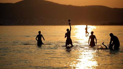 People play in the sea during sunset in the outskirts of Izmir, western Turkey. Emre Tazegul / AP Photo