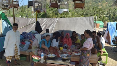 Women prepare meals underneath songbirds kept in cages at a temporary shelter in Pemenang, Northern Lombok. AFP