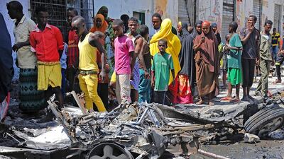 Bystanders look at the wreckage of a car bomb attack in Mogadishu on April 21, 2015. Three people were killed and six wounded in a car bomb blast outside a popular restaurant in the centre of the Somali capital Mogadishu. AFP PHOTO /Mohamed Abdiwahab