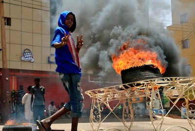 A child gestures as he walks past burning tyres near Khartoum's army headquarters. AFP